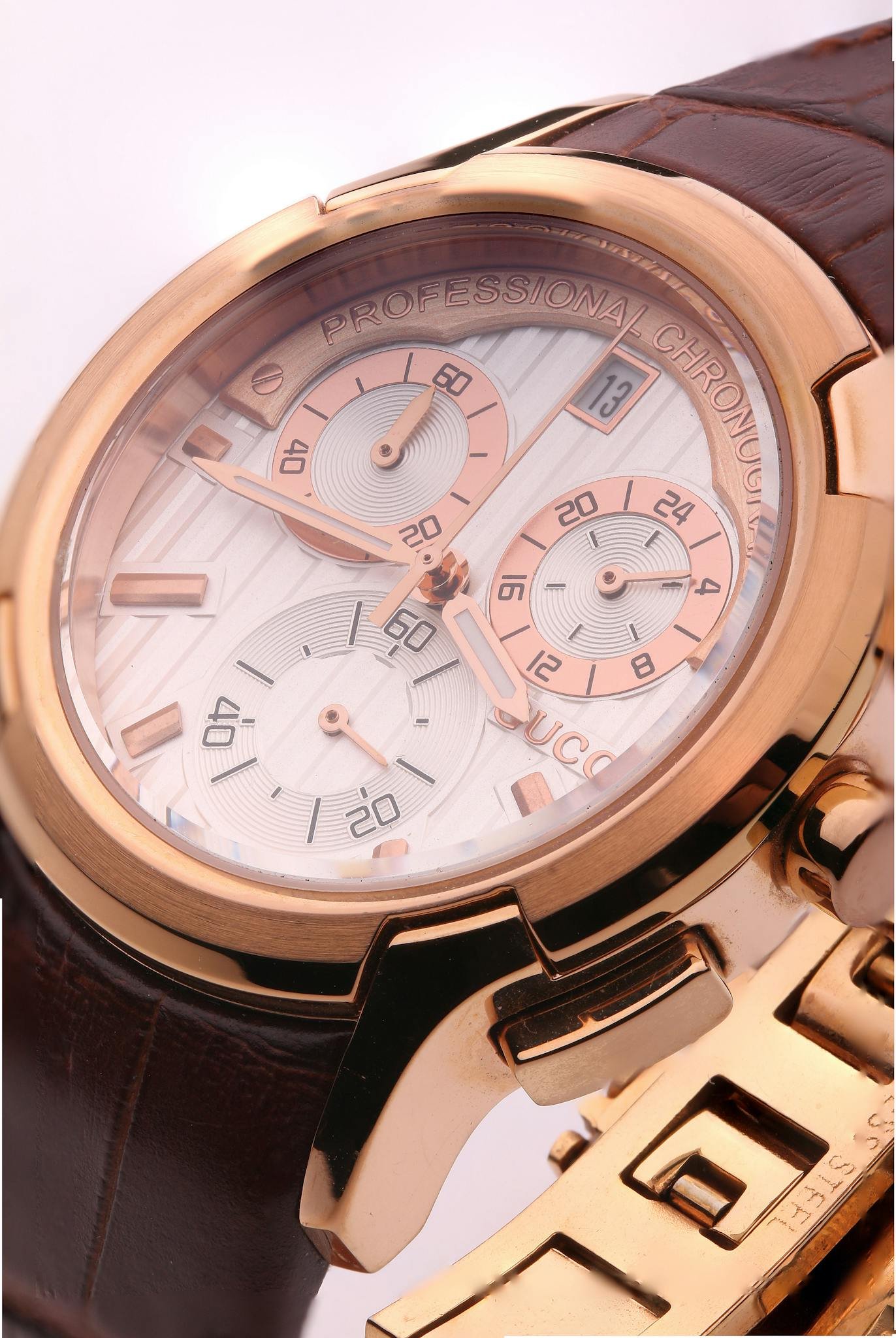 Detailed close-up of a luxurious gold chronograph watch with brown leather strap.